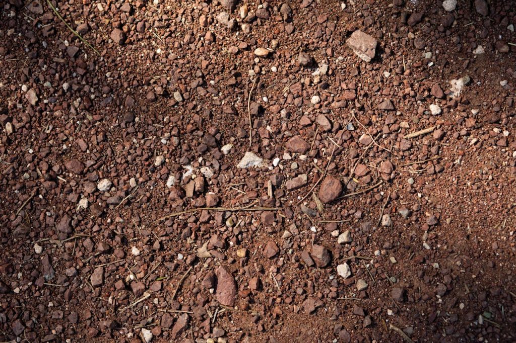 Detailed texture of red rocky soil with natural shadows, showcasing earth patterns.